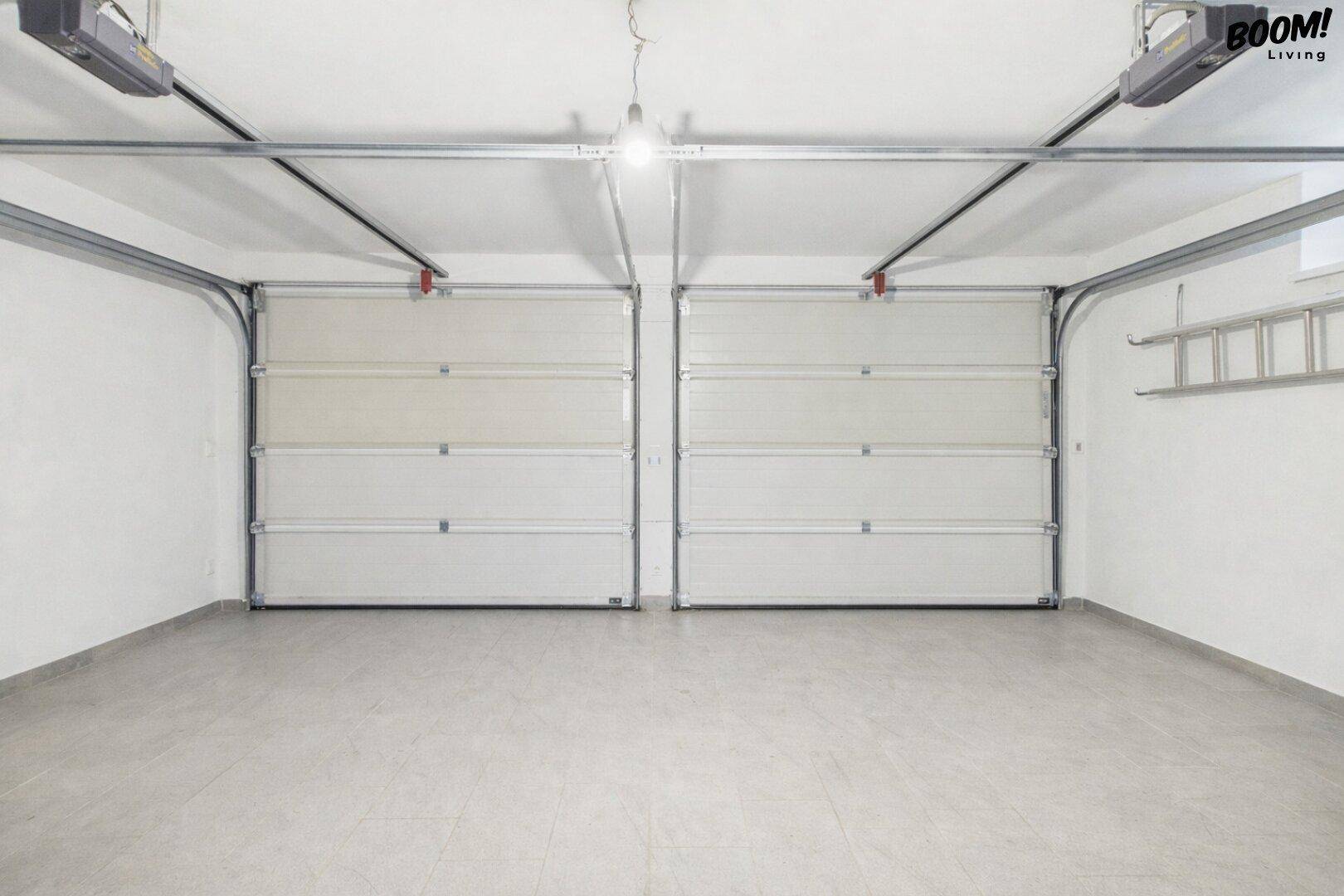 Saubere und leere Doppelgarage mit zwei automatischen Sektionaltoren und viel Platz.