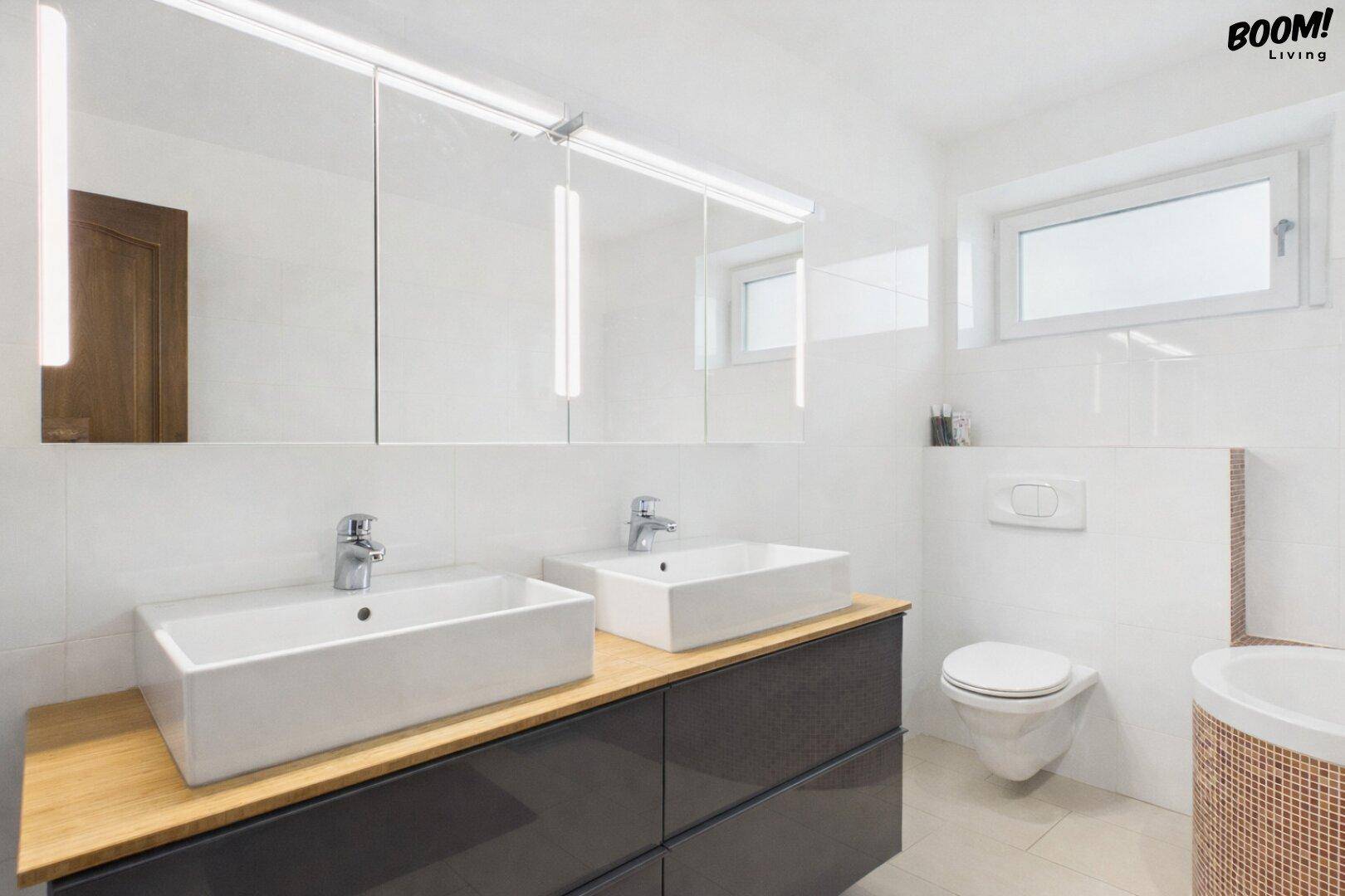 Modernes Badezimmer mit Doppelwaschbecken, Spiegelschrank und Wand-WC.