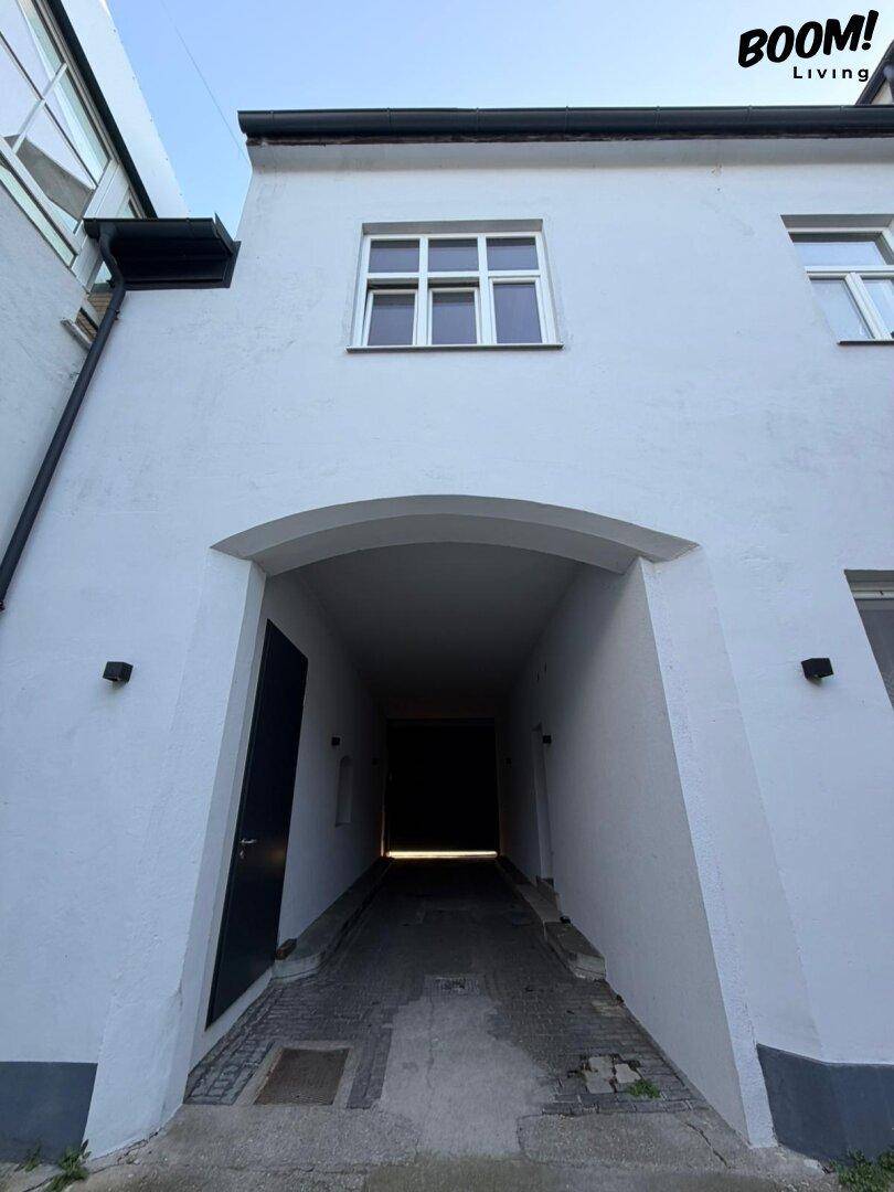 Gebäudeeingang mit einem Torbogen, der zu einem dunklen Durchgang führt.