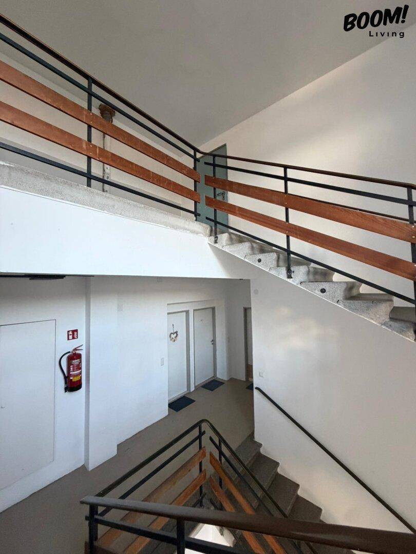 Treppenhaus mit mehreren Etagen, Steinstufen und Holzgeländer in einem Altbau.