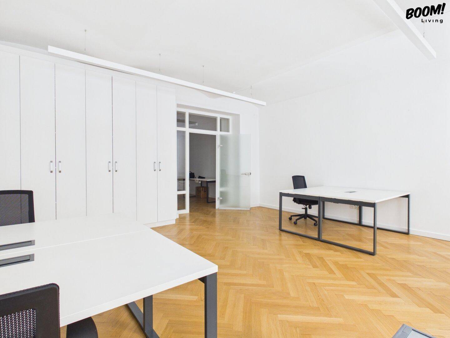 Großes Büro mit Fischgrätparkett, Einbauschränken und Zugang zu einem weiteren Raum.