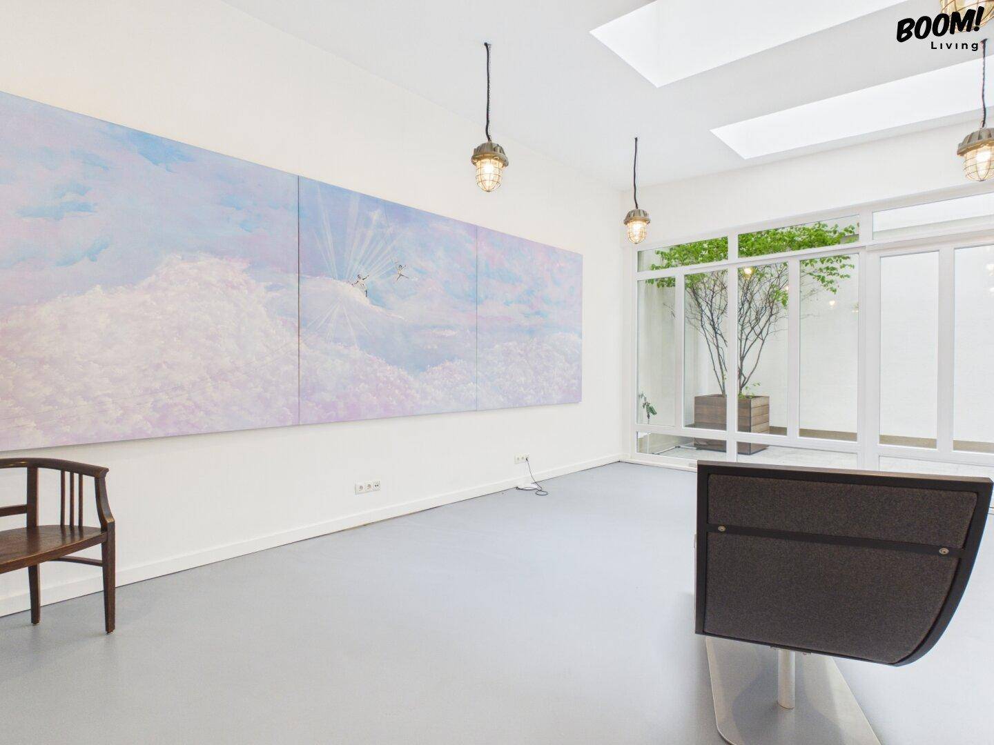 Geräumiger Bürobereich mit Kunst an der Wand, Oberlichtern und einem Blick auf einen Innenhof.