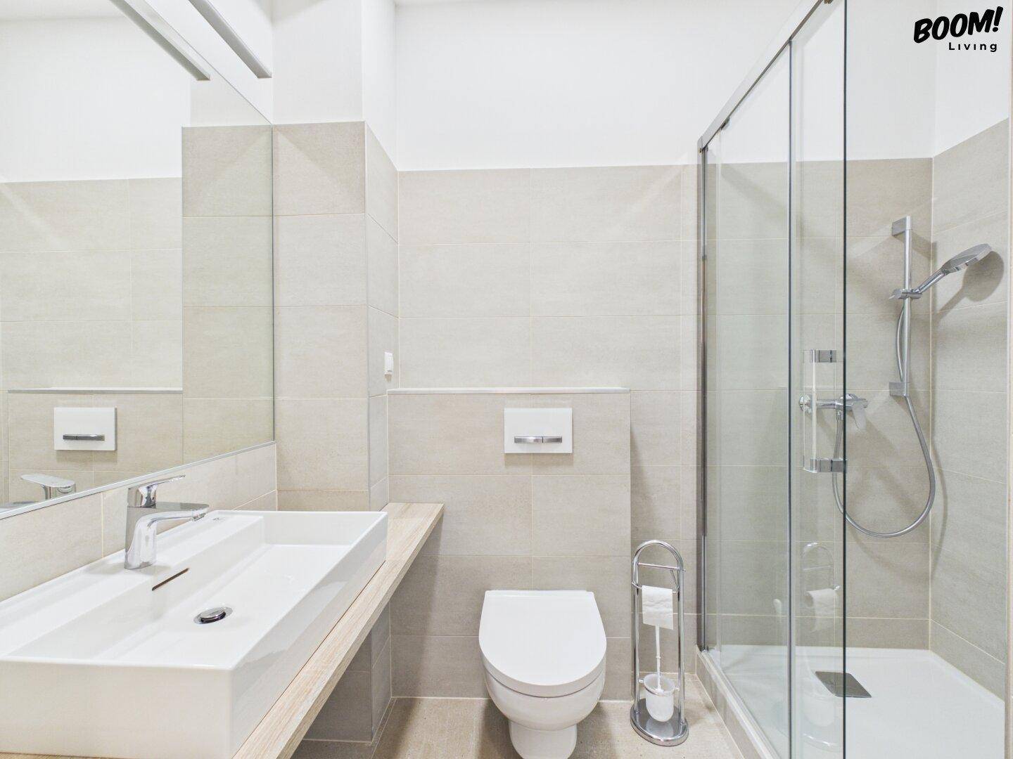 Modernes Badezimmer mit begehbarer Dusche, wandhängendem WC und großformatigen Fliesen.