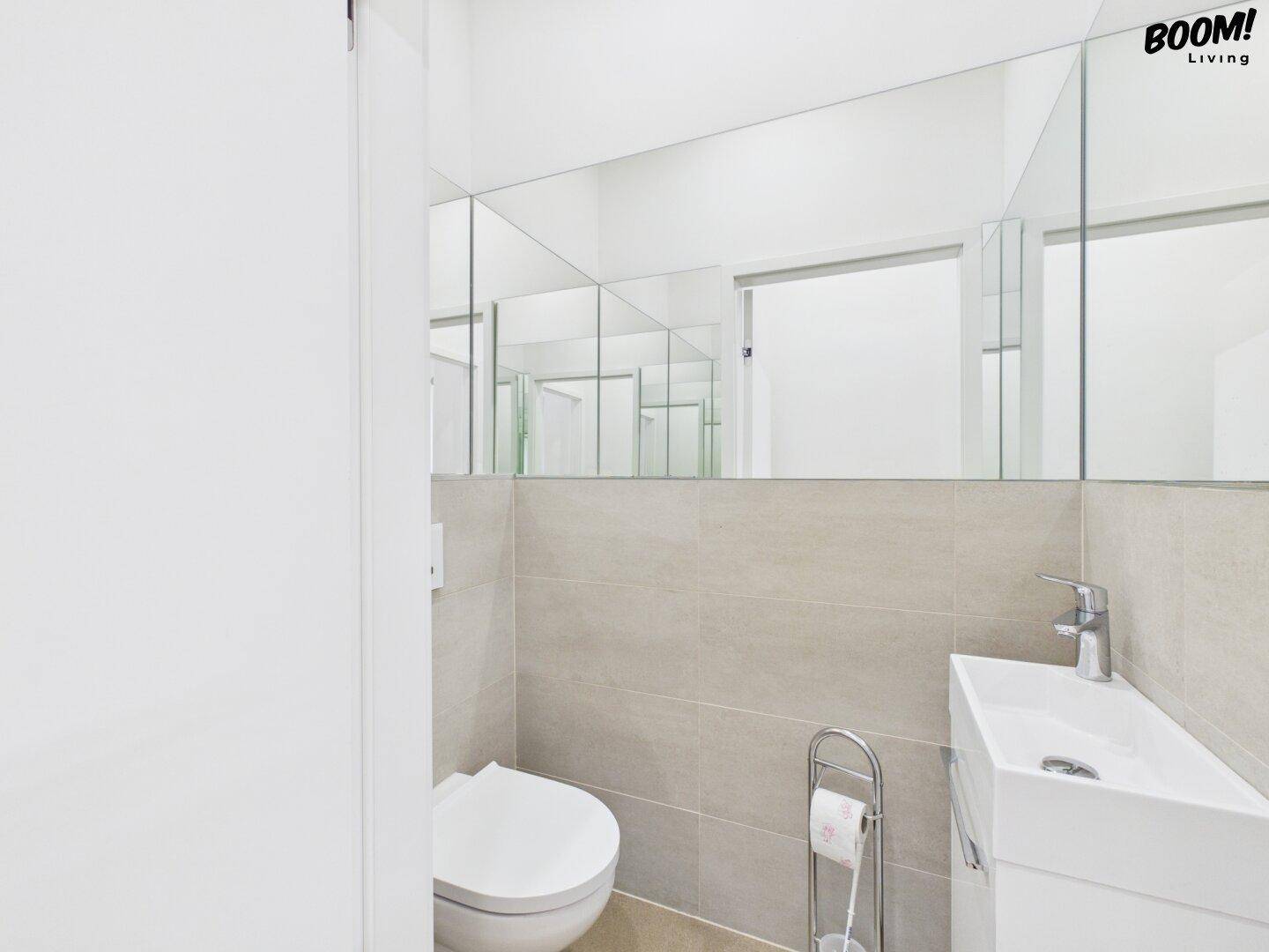 Modernes Gäste-WC mit wandhängendem WC, kleinem Waschbecken und Spiegelflächen.