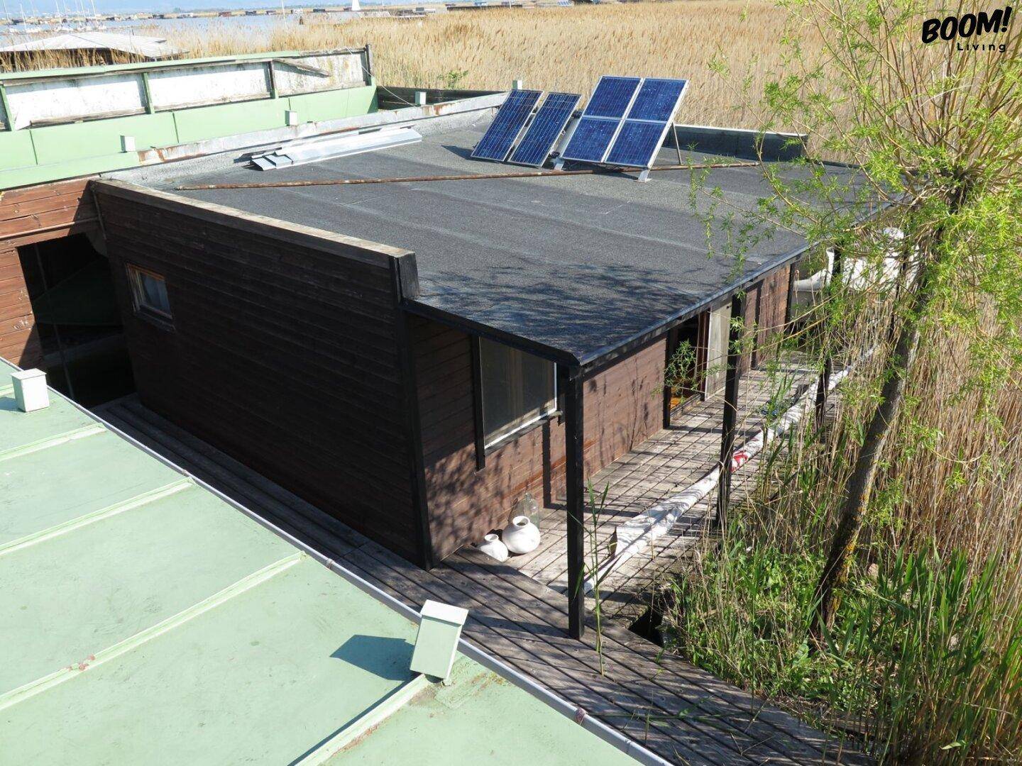 Hausboot von oben mit Solarmodulen auf dem Flachdach und umliegender Natur am Wasser.