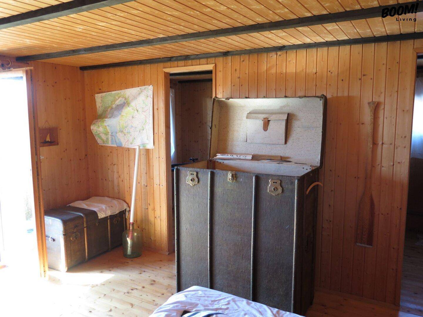 Schlafzimmer mit Holzvertäfelung, Holzboden und Vintage-Truhen als dekorative Elemente.