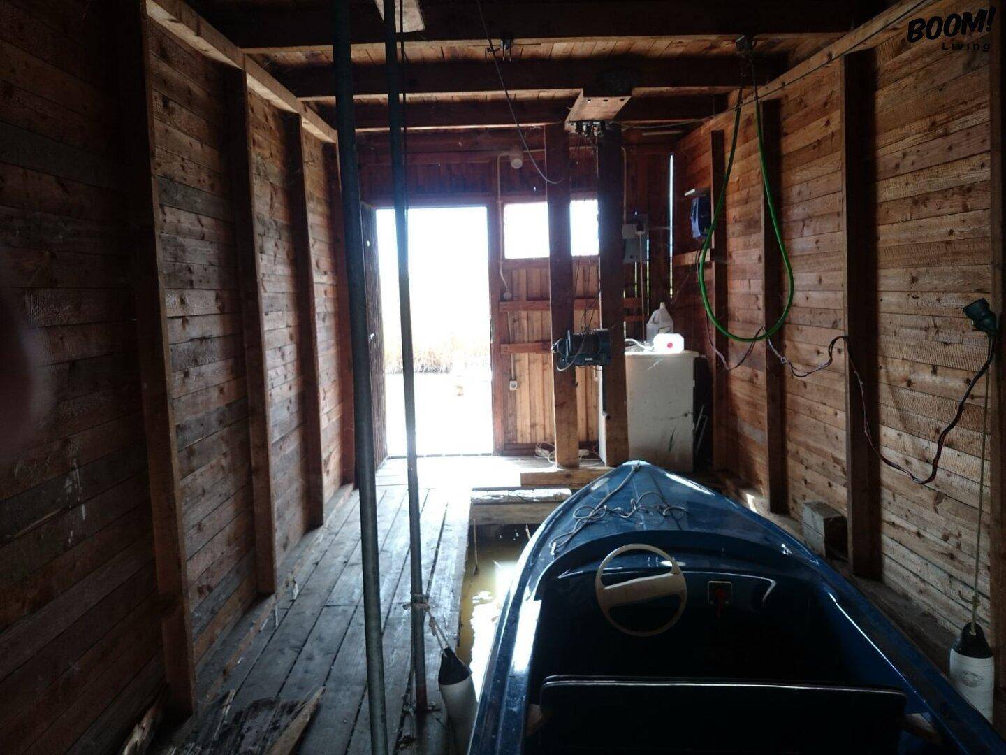 Innenansicht eines Bootshauses mit einem Boot und Blick auf den hellen Wasserausgang.