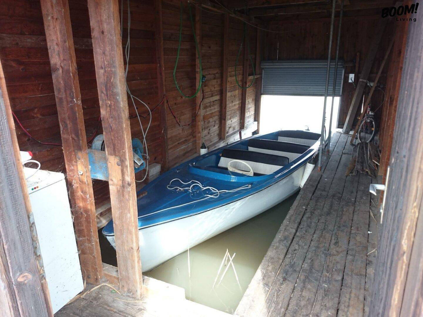 Innenansicht eines Bootshauses mit einem blauen Boot und robuster Holzkonstruktion.
