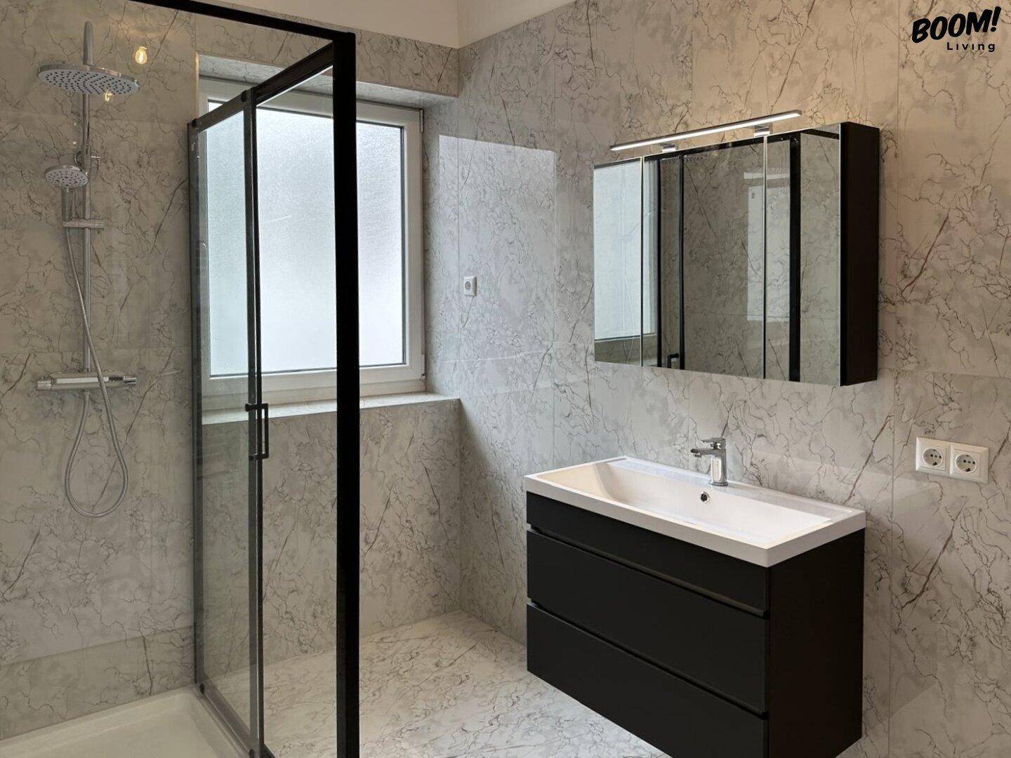 Modernes Badezimmer mit großer Dusche, Waschbeckenunterschrank und Spiegelschrank.