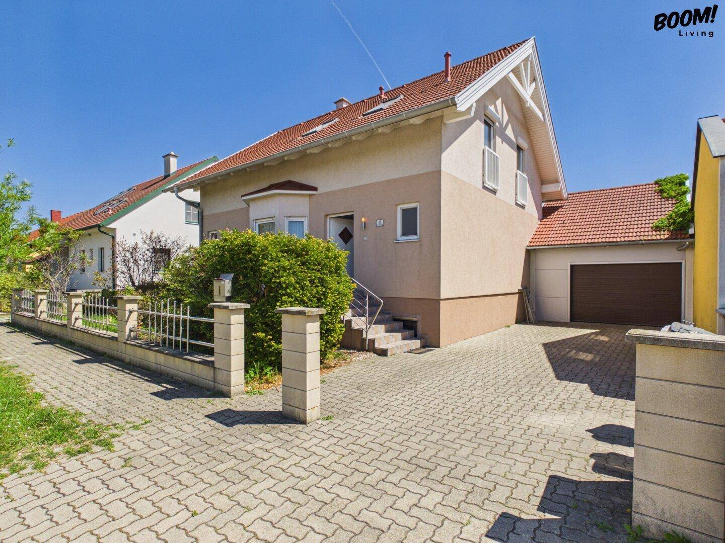 Ansicht des Einfamilienhauses mit gepflasterter Auffahrt und integrierter Garage.