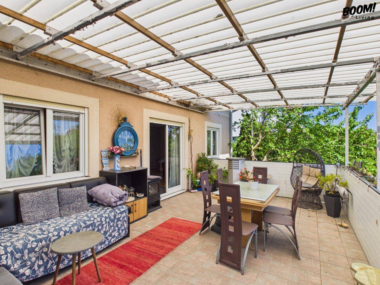 Geräumige überdachte Terrasse mit Essbereich, Lounge-Möbeln und Zugang zum Garten.