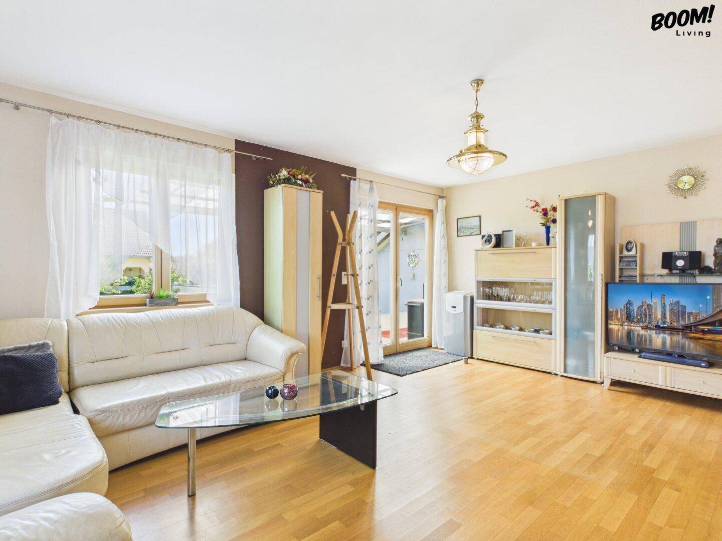 Gemütliches Wohnzimmer mit Parkettboden, hellen Möbeln und Zugang zur Terrasse.