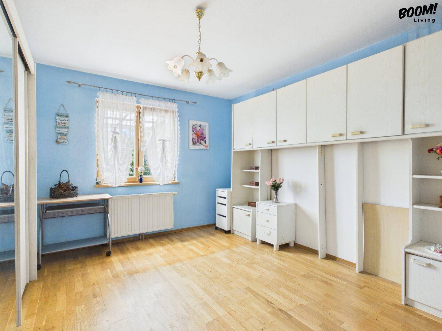 Helles Schlafzimmer mit blauen Wänden, Parkettboden und Einbauschränken.