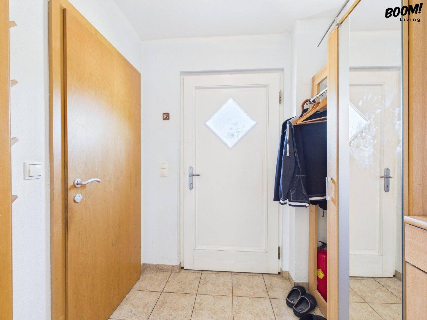 Eingangsbereich mit Fliesenboden, Garderobe und Holztüren.