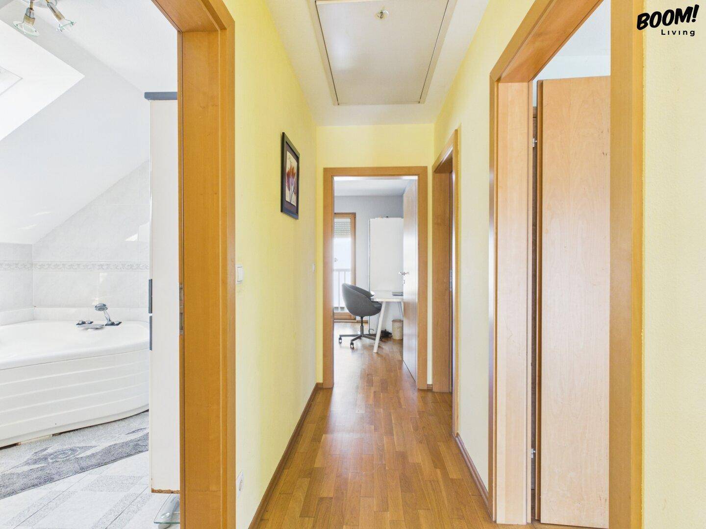 Flur mit Parkettboden, gelben Wänden und Blick in angrenzende Zimmer.