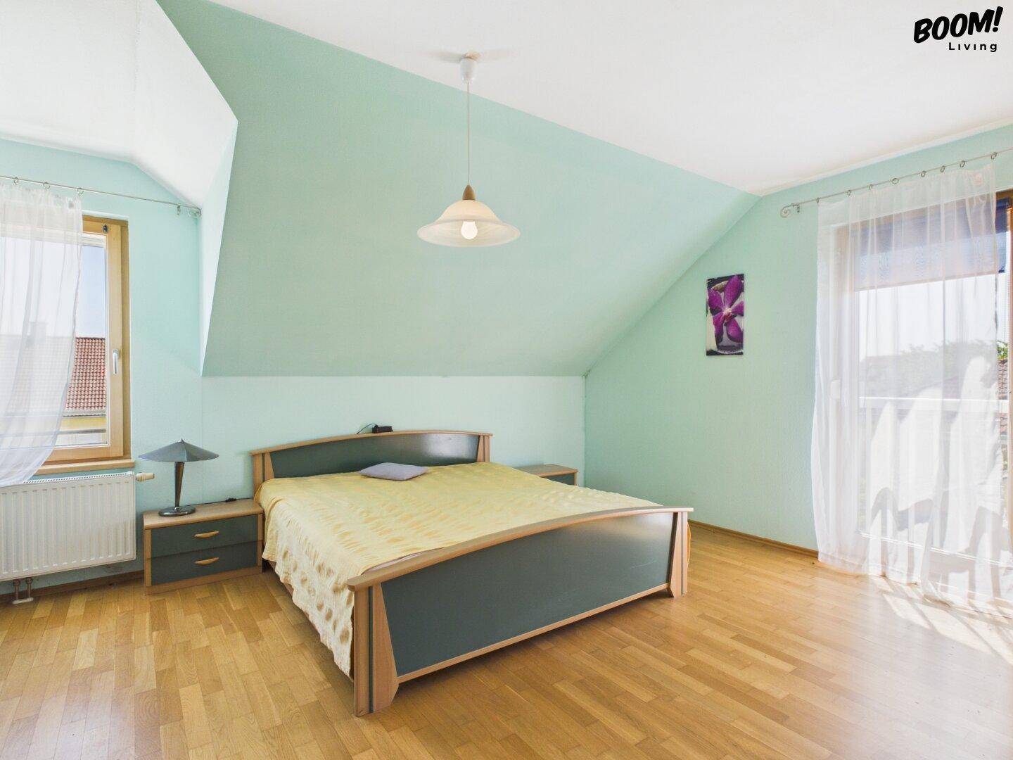 Schlafzimmer im Dachgeschoss mit mintgrünen Wänden, Parkettboden und Dachschräge.