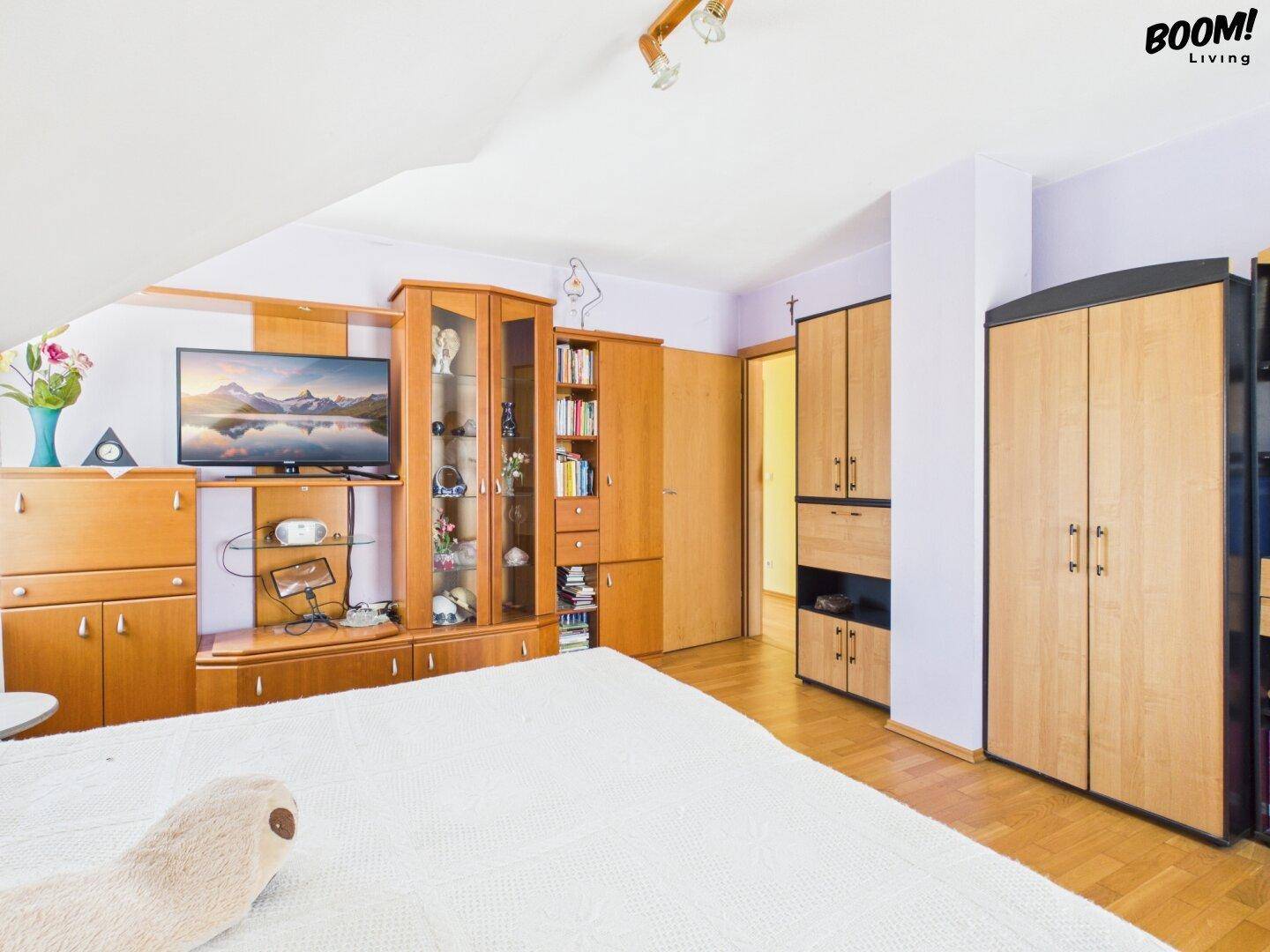 Geräumiges Schlafzimmer mit Holzmöbeln, Parkettboden und viel Stauraum.