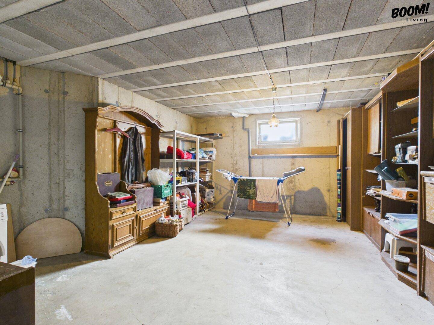Geräumiger Kellerraum mit Betonboden, Regalen und einem kleinen Fenster.