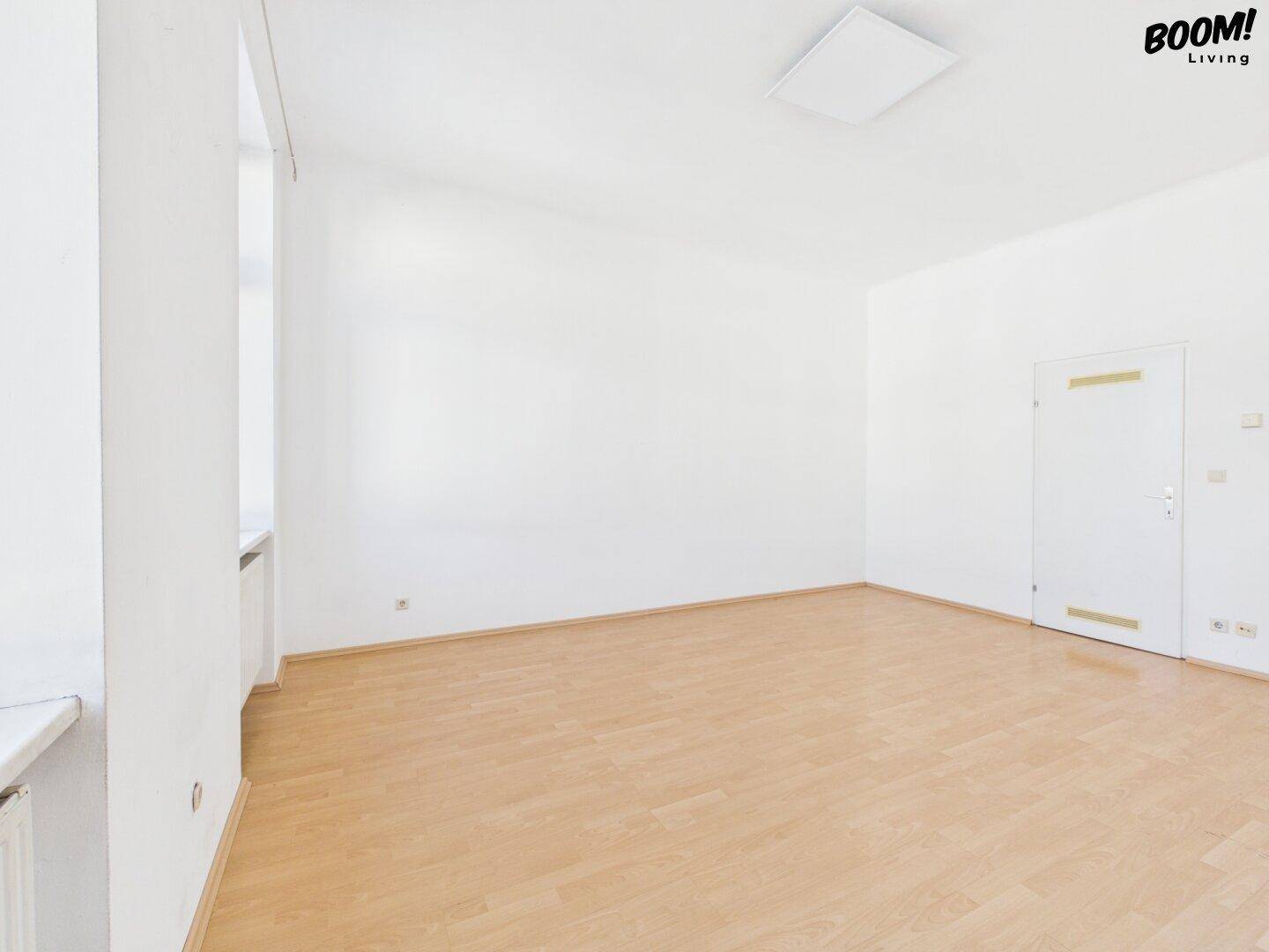 Geräumiges, leeres Zimmer mit Parkettboden und weiß gestrichenen Wänden, ideal für neue Mieter.