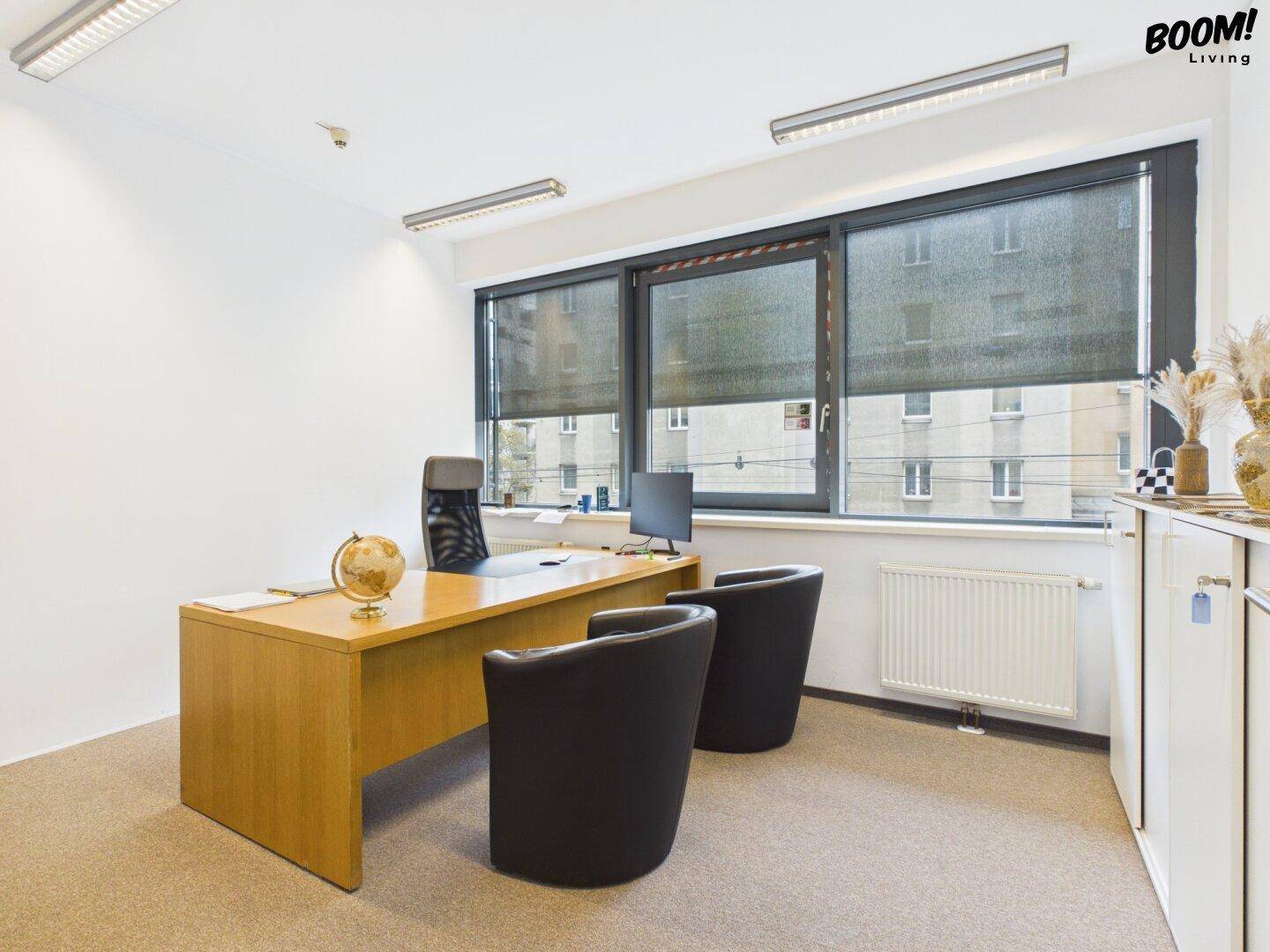 Helles Büro mit großem Schreibtisch, ergonomischem Stuhl und Blick auf die Stadt durch die Fenster.
