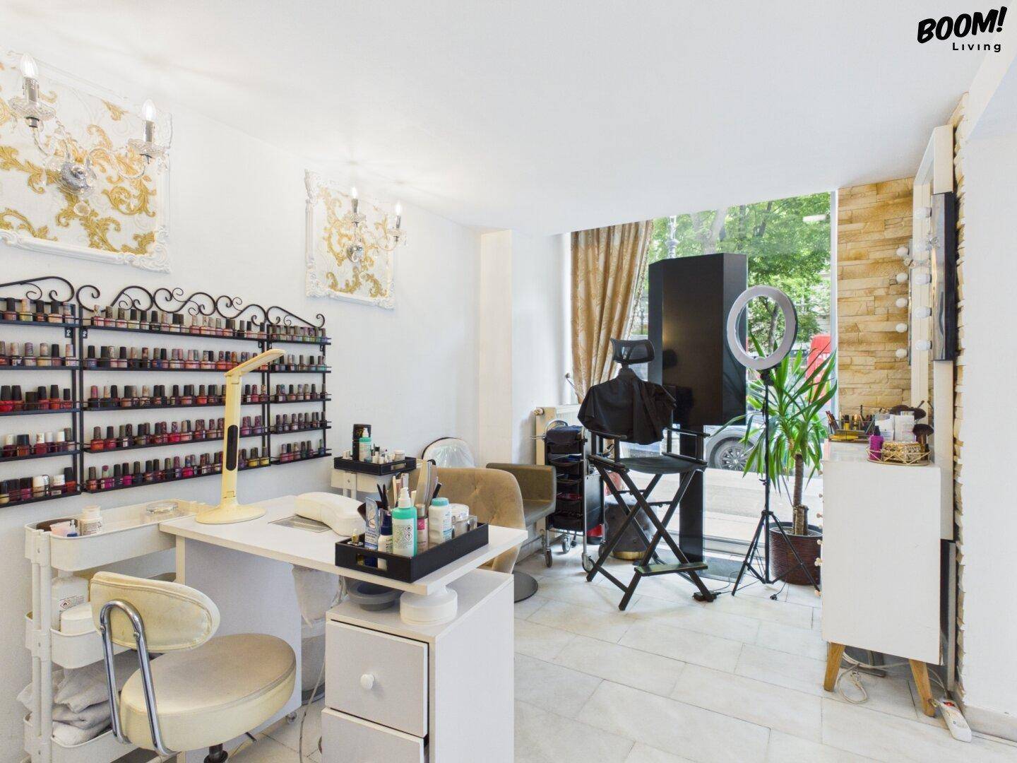 Bereich für Nagelpflege mit einem großen Regal voller Nagellacke, einem Arbeitstisch und einem Fenster.