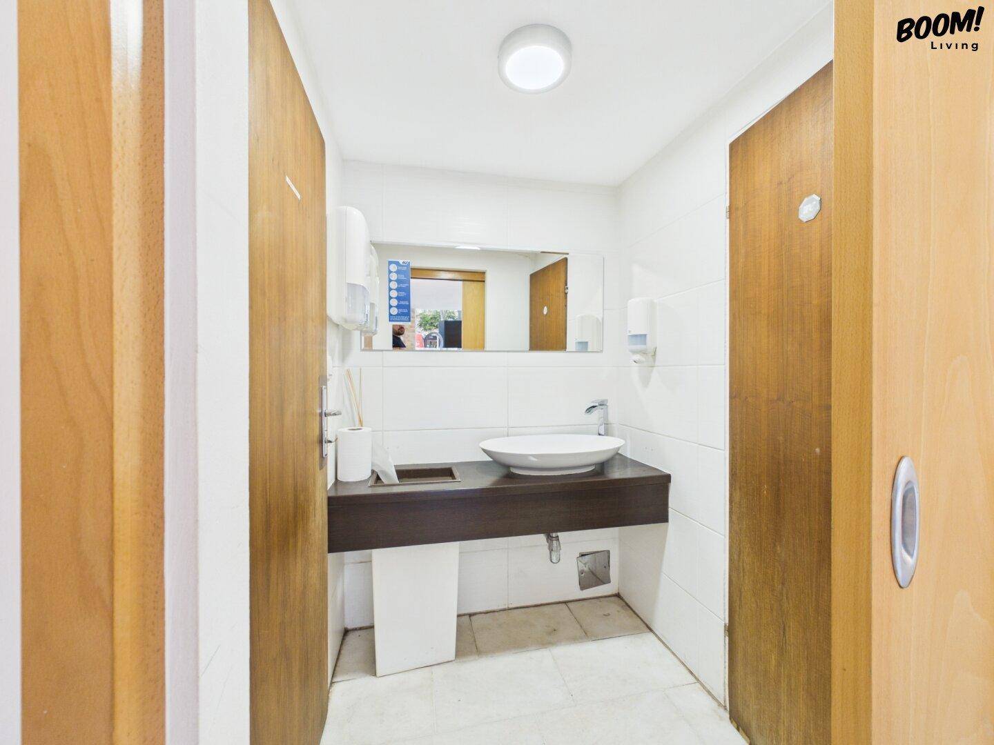 Modernes Badezimmer mit weiß gefliesten Wänden, einem Aufsatzwaschbecken und einem großen Spiegel.