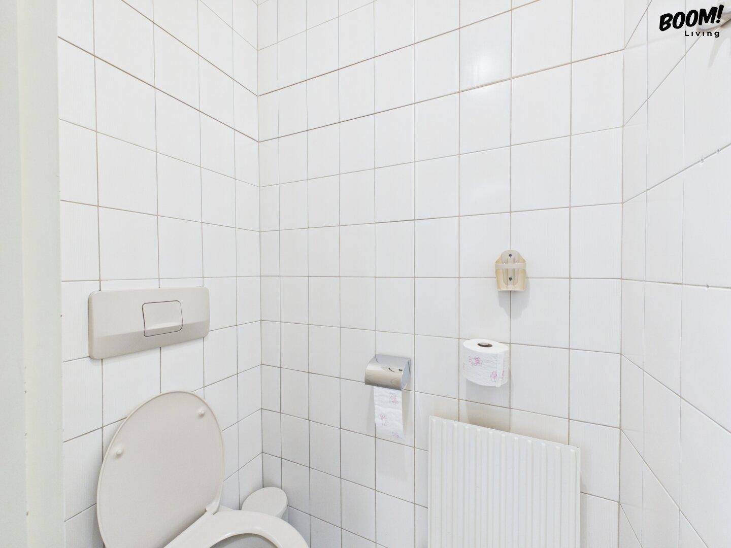 Kleine Toilette mit weißen Fliesen an Wänden und Boden, funktional und sauber.