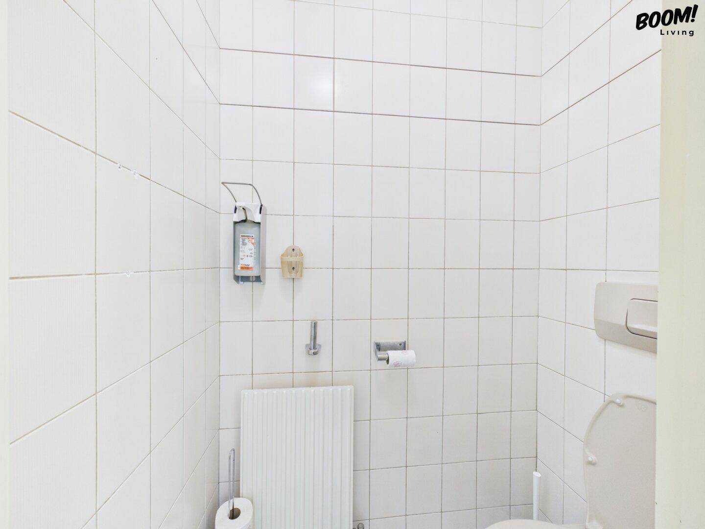 Kleine Toilette mit weißen Fliesen an Wänden und Boden, funktional und sauber.
