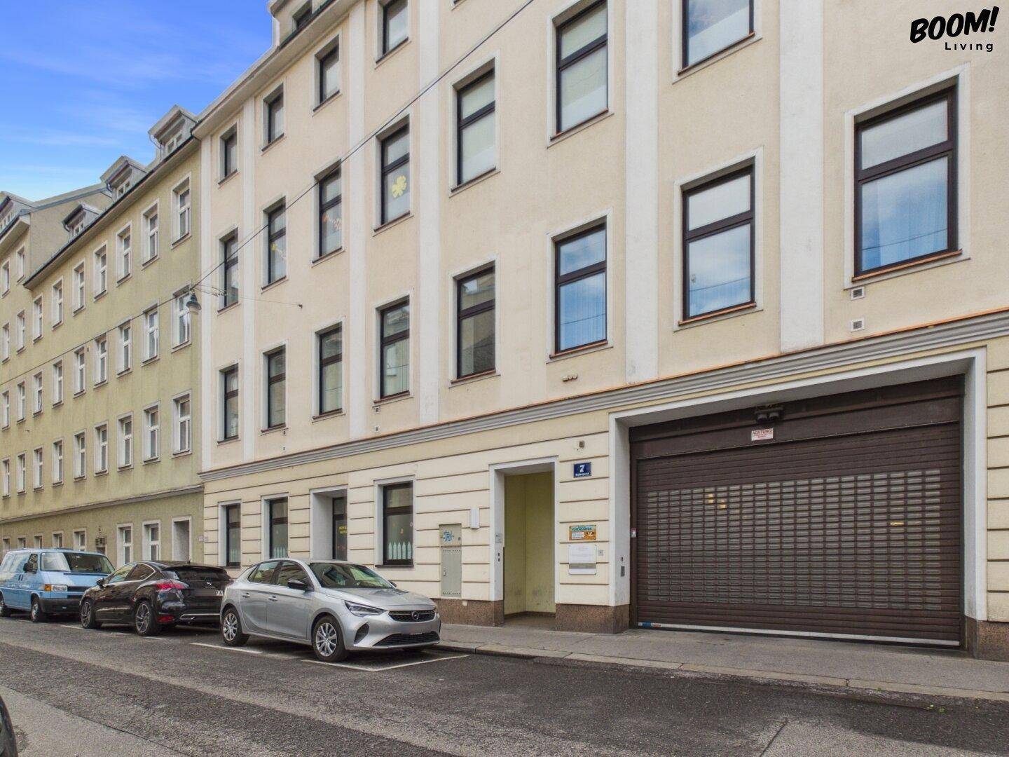 Fassade eines Gebäudes an der Straße mit mehreren Fenstern und einem großen Garagentor.