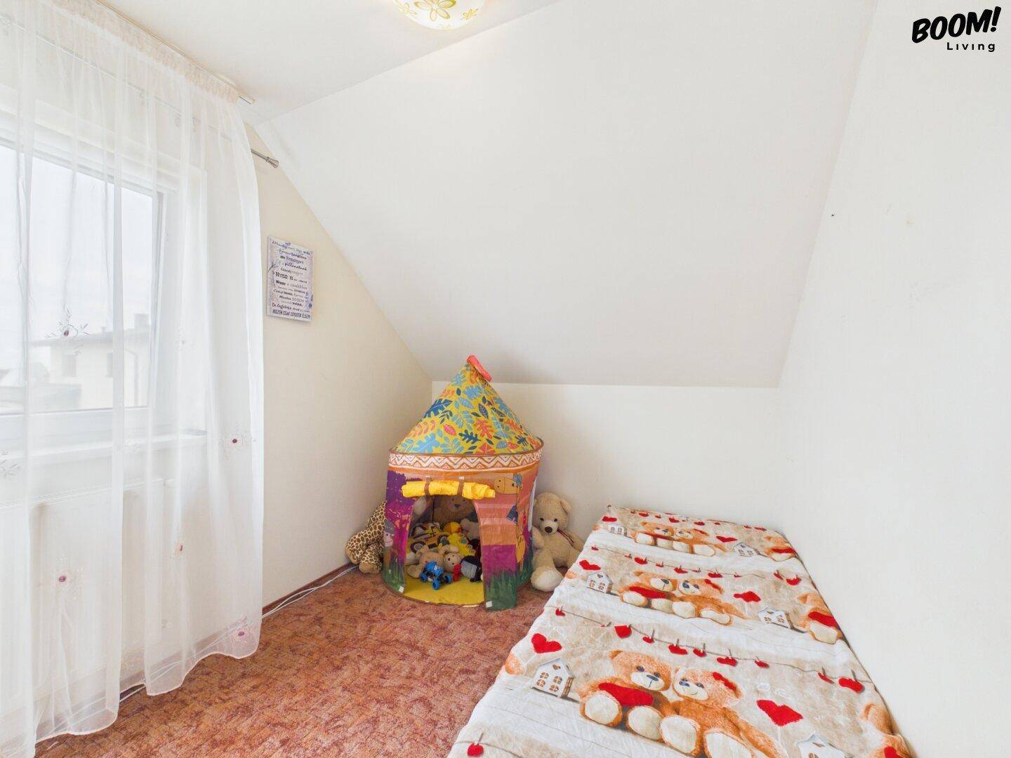 Kinderzimmer im Dachgeschoss mit schrägen Wänden, Fenster und Spielzelt.