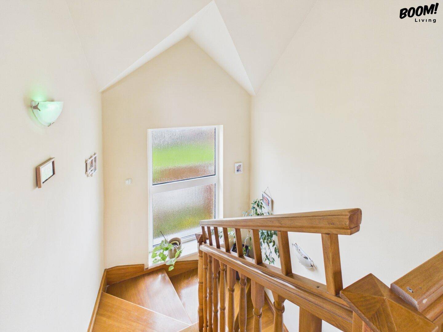 Holztreppe mit Geländer, die in das Obergeschoss führt, mit einem Fenster für natürliches Licht.
