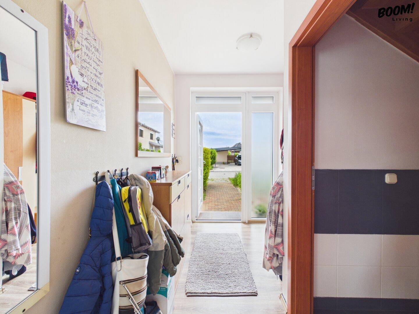 Eingangsbereich mit Garderobe, Spiegel und Blick durch die Haustür ins Freie.
