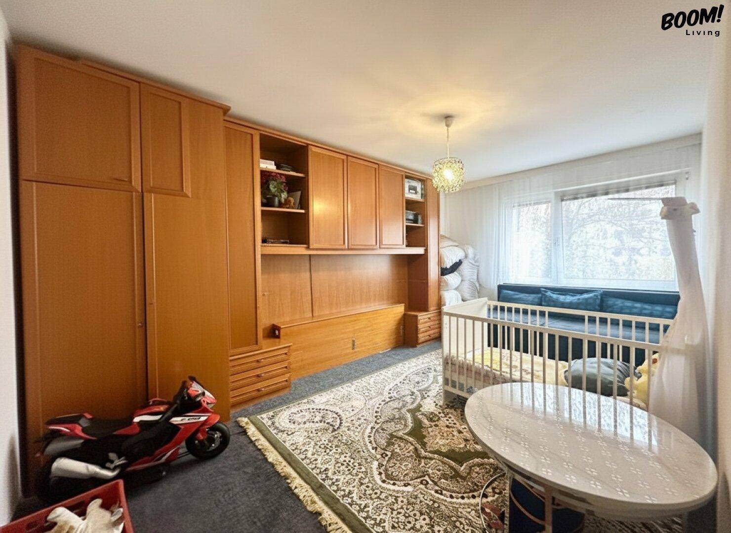 Kinderzimmer mit großem Einbauschrank aus Holz, Babybett und Teppichboden.