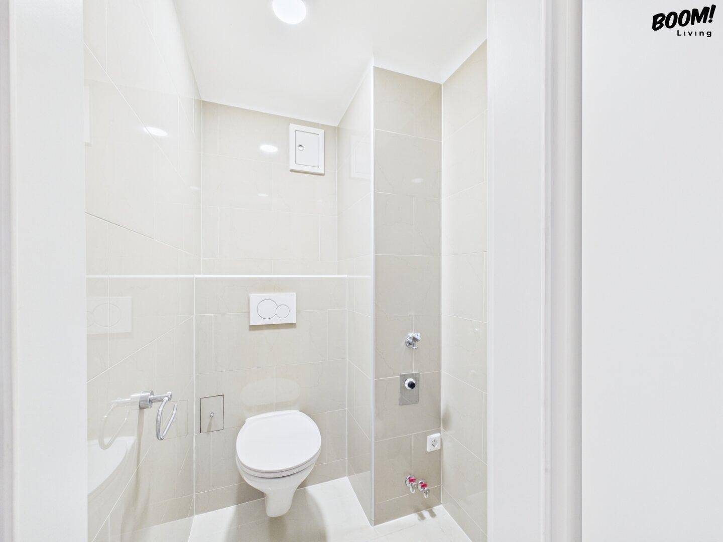 Modernes Gäste-WC mit beigen Fliesen und wandhängender Toilette, platzsparend und funktional.