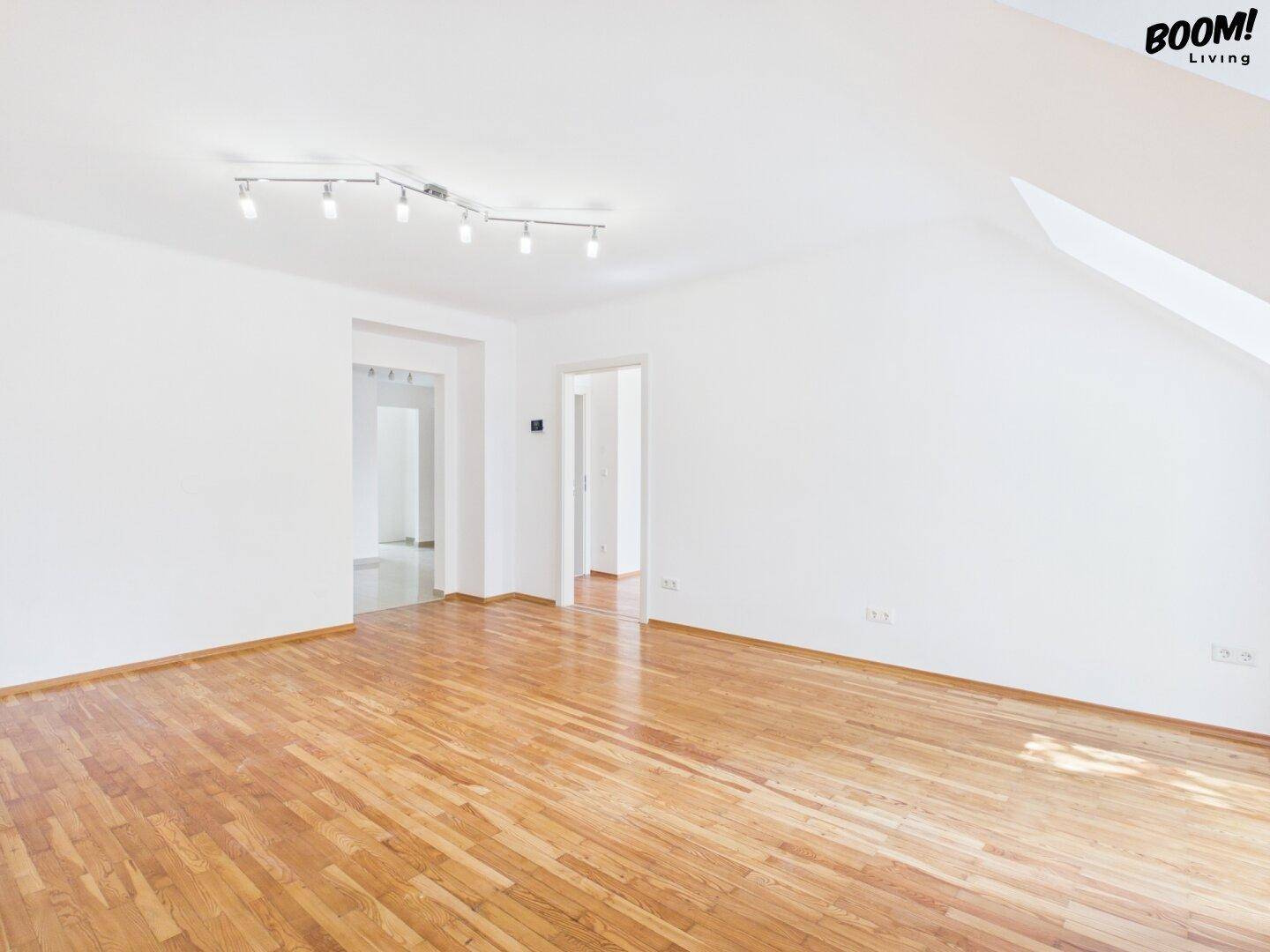 Heller, leerer Raum mit Parkettboden und Zugang zu weiteren Zimmern, ideal für individuelle Gestaltung.