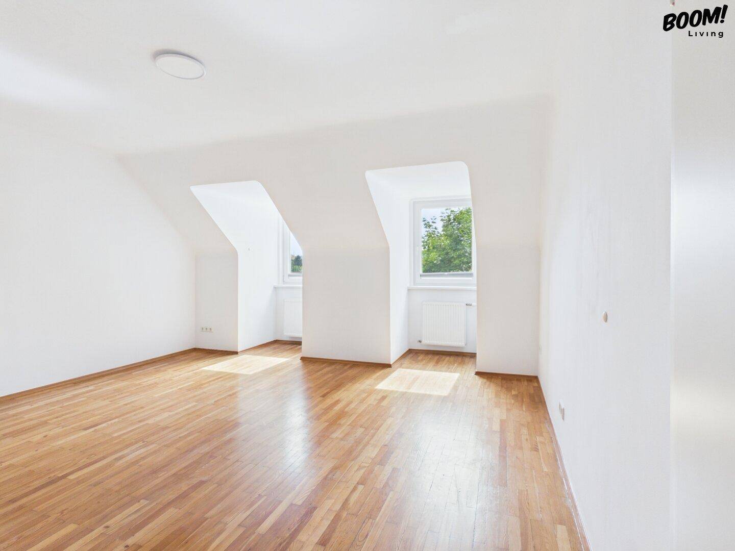 Heller, leerer Raum mit Parkettboden und zwei Fenstern, ideal als Schlafzimmer oder Kinderzimmer.