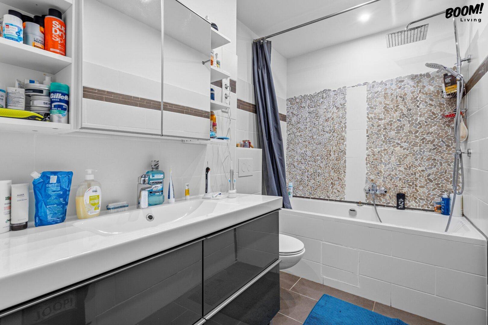 Modernes Badezimmer mit Badewanne, Duschvorhang und einem einzelnen Waschbecken mit Spiegelschrank.