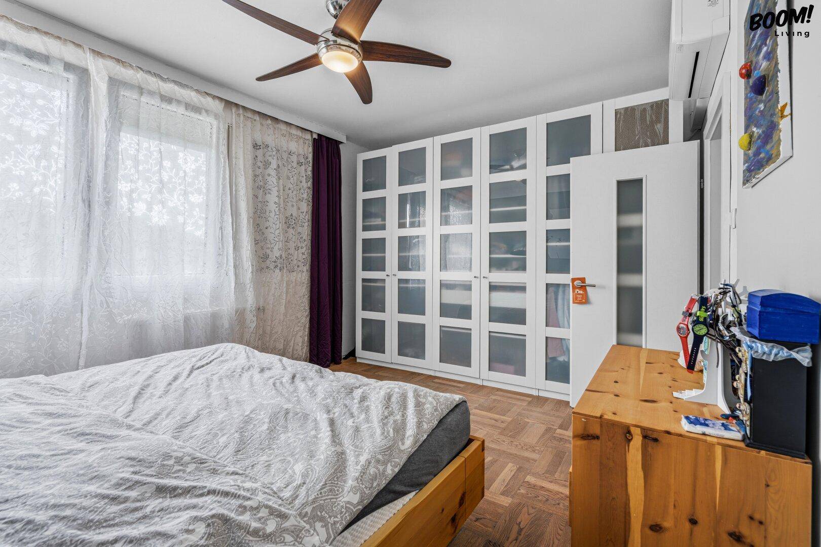 Schlafzimmer mit Holzboden, Einbauschränken und großem Fenster für viel Tageslicht.