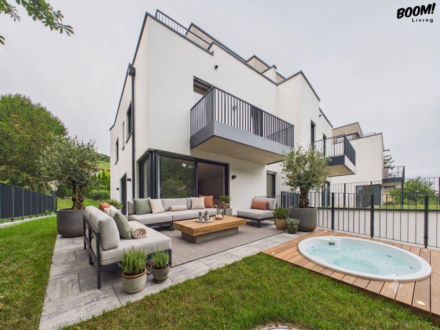 Große Terrasse mit Outdoor-Sitzbereich, Whirlpool und Blick auf die moderne Architektur des Hauses.