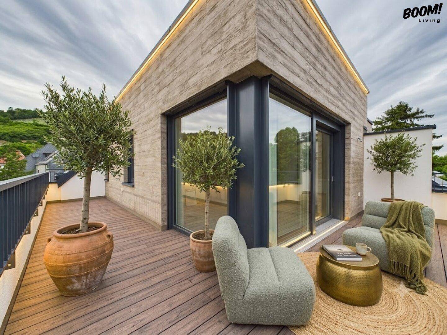 Stilvolle Dachterrasse mit Holzboden, bequemen Sitzmöbeln und dekorativen Olivenbäumen.