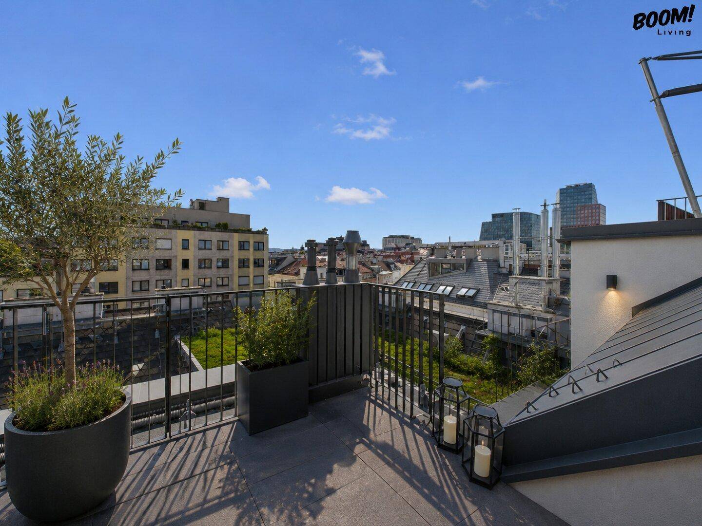 Weitläufige Dachterrasse mit Stadtblick, Pflanzen und modernen Geländern unter blauem Himmel.