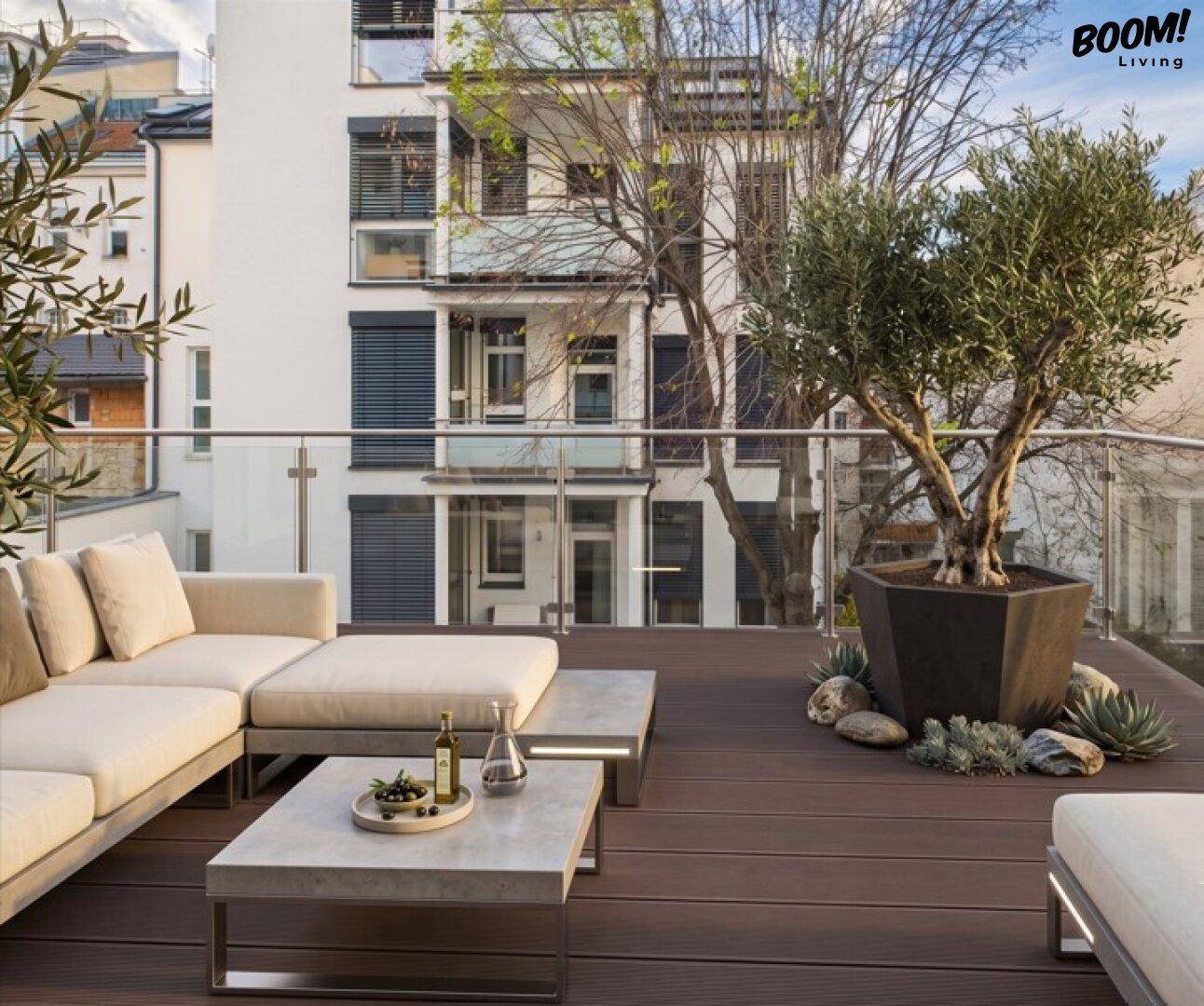 Geräumige Dachterrasse mit Lounge-Möbeln, Holzboden und Blick auf die Stadt.