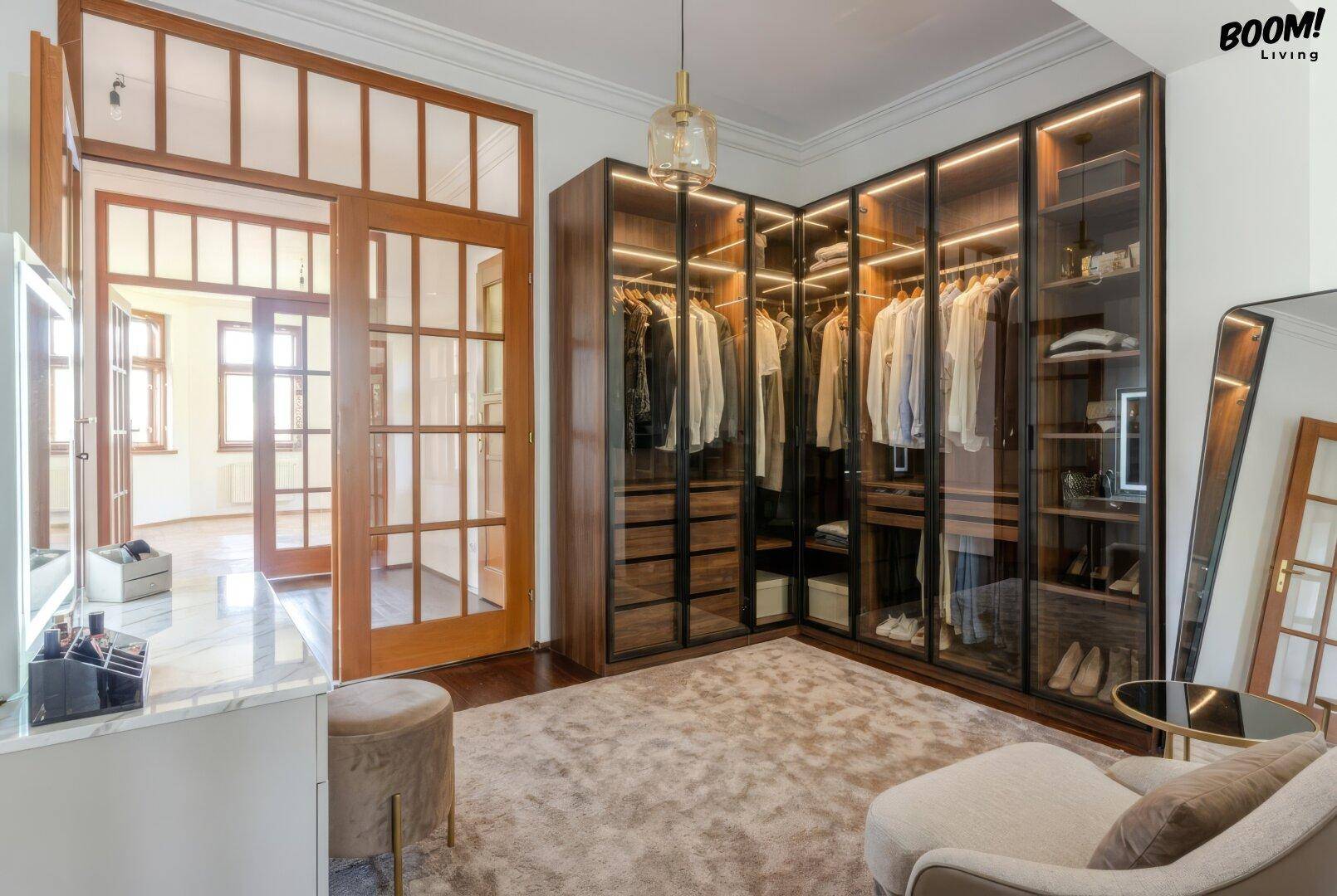 Luxuriöser begehbarer Kleiderschrank mit beleuchteten Glasvitrinen und viel Stauraum.