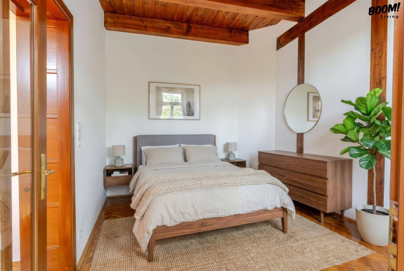 Schlafzimmer mit Holzbalkendecke, Parkettboden und modernem Bett in warmen Holztönen.