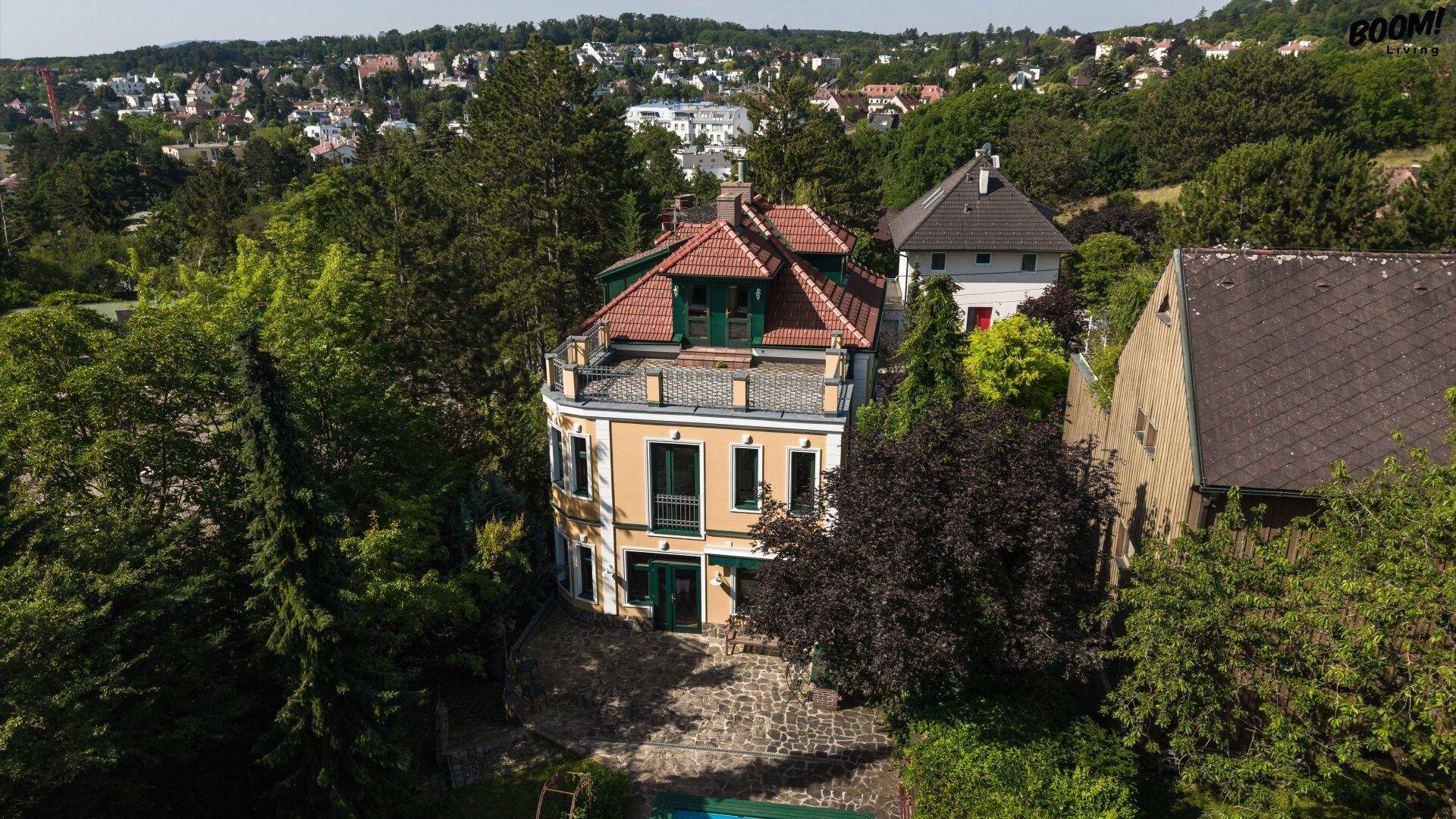 Luftaufnahme der Villa mit gelber Fassade, grünen Fensterläden und weitem Blick über die Stadt.