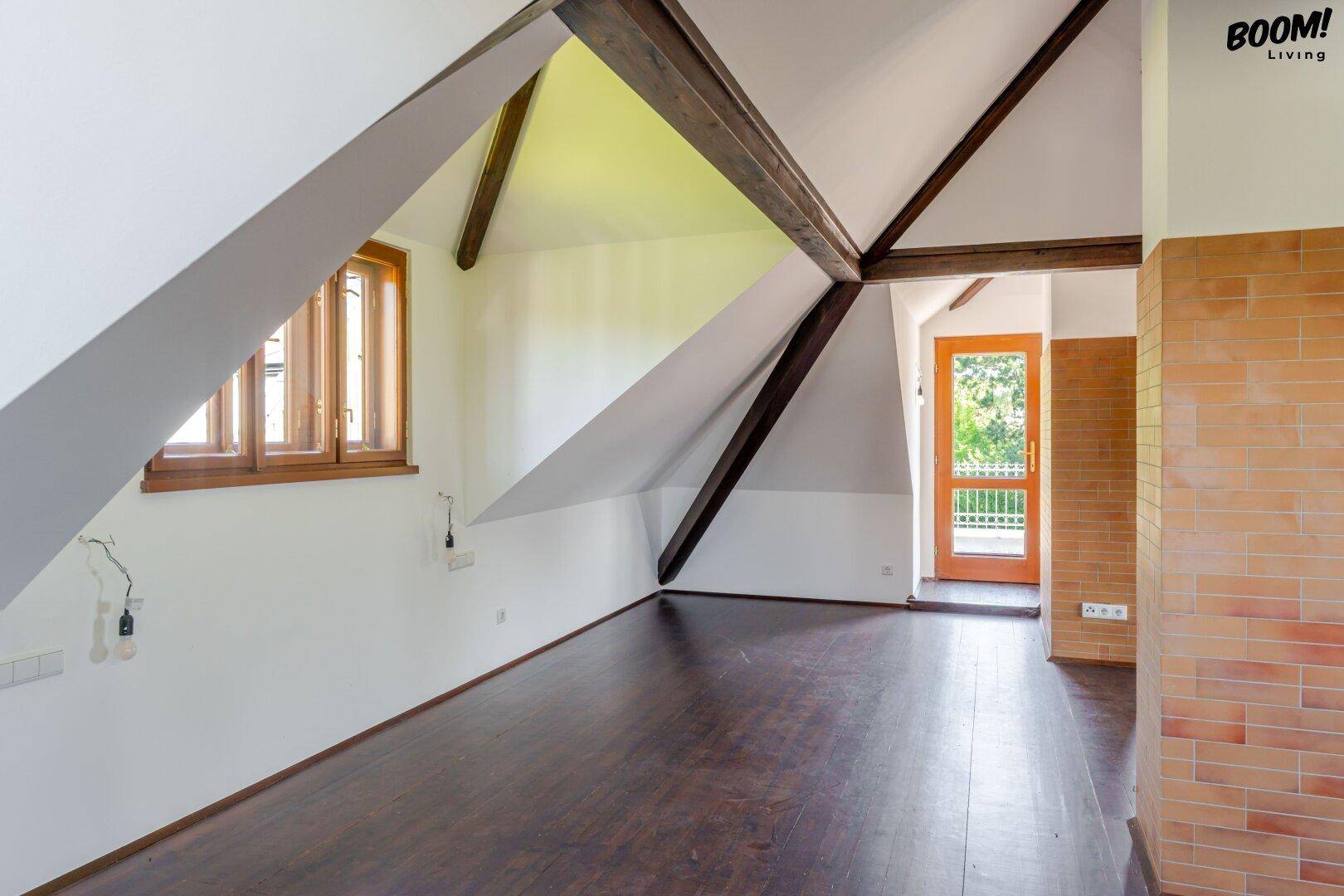 Heller Dachbodenraum mit sichtbaren Holzbalken, schrägen Decken und dunklem Holzboden.