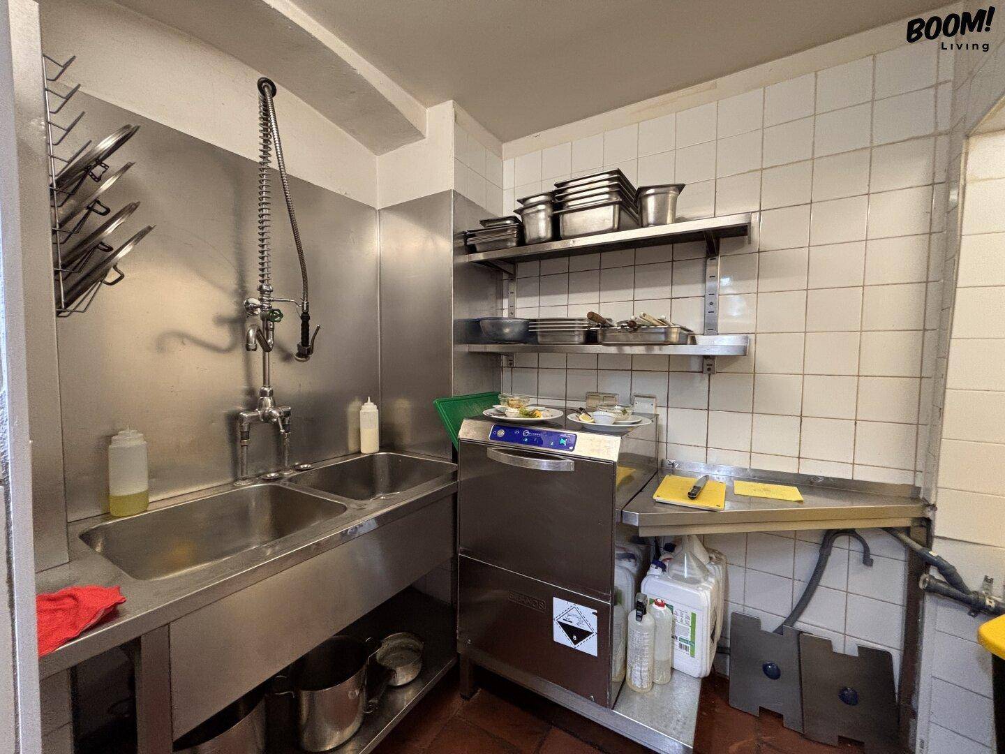 Spülbereich einer Gewerbeküche mit großen Edelstahlbecken und professioneller Spülmaschine.
