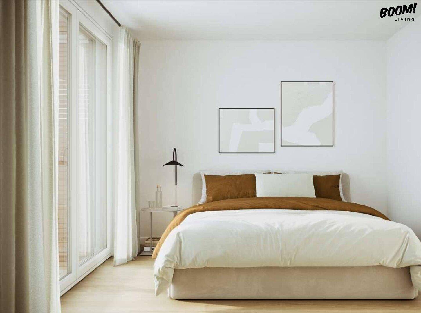 Helles Schlafzimmer mit Doppelbett, minimalistischer Einrichtung und Zugang zu einem Balkon.
