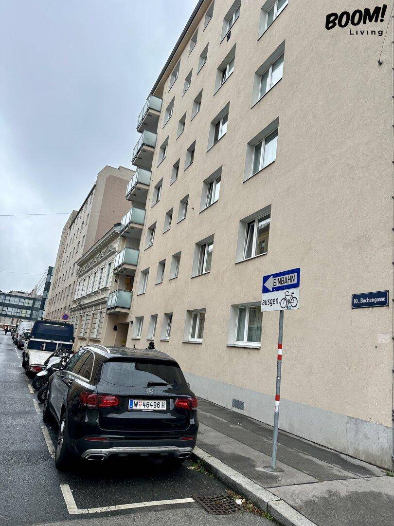 Ansicht der Gebäudefassade von der Straße mit geparkten Autos und Straßenschildern.