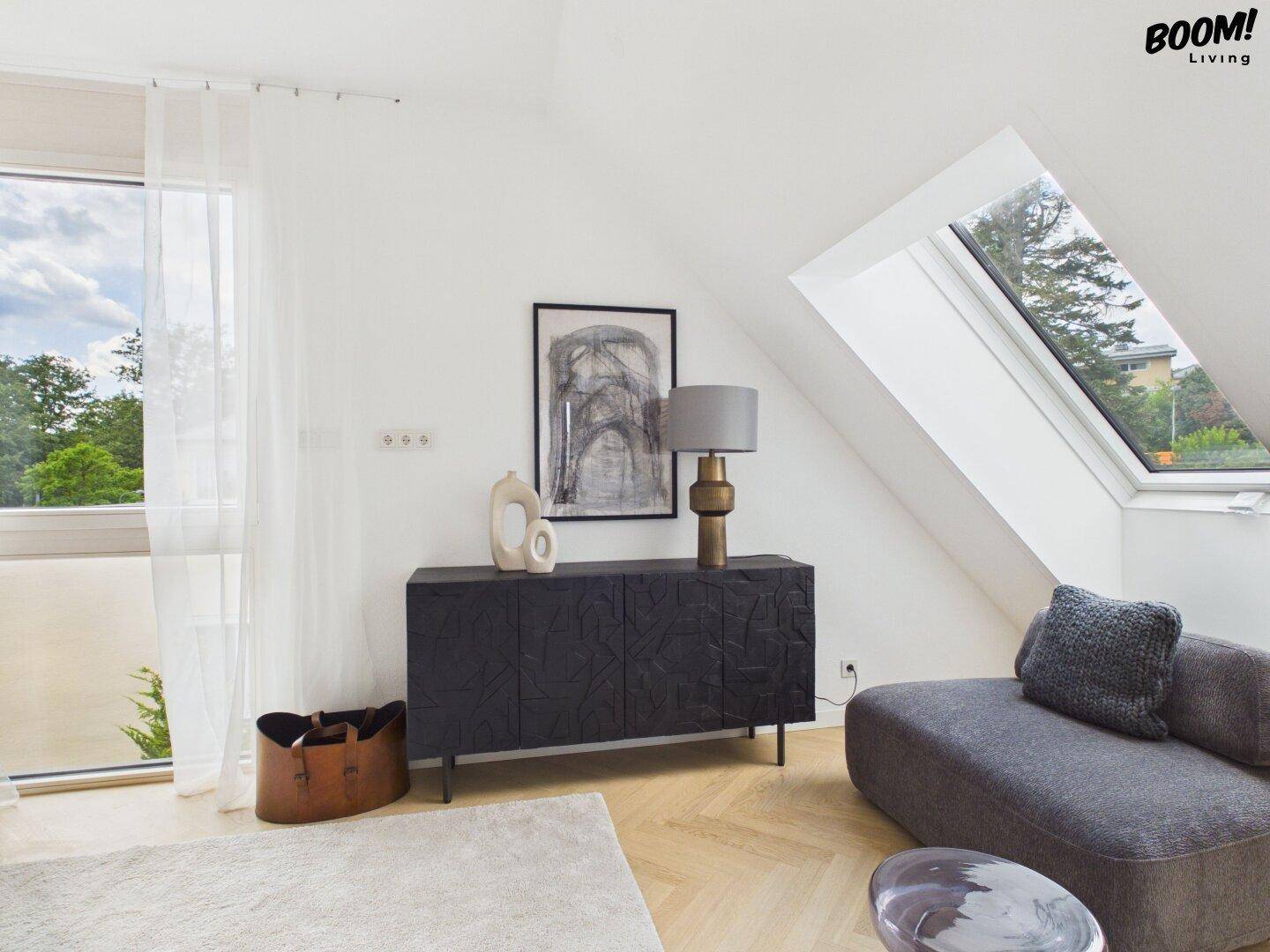 Heller Wohnbereich mit Dachschrägen, modernem Sideboard und großem Dachfenster.